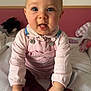 baby, infant, child, pink_clothing, overalls, sitting, blanket, indoor, face, hands, playful, cute, soft_toys, expression, person, head, tongue_out, bright_eyes, cozy_room, casual