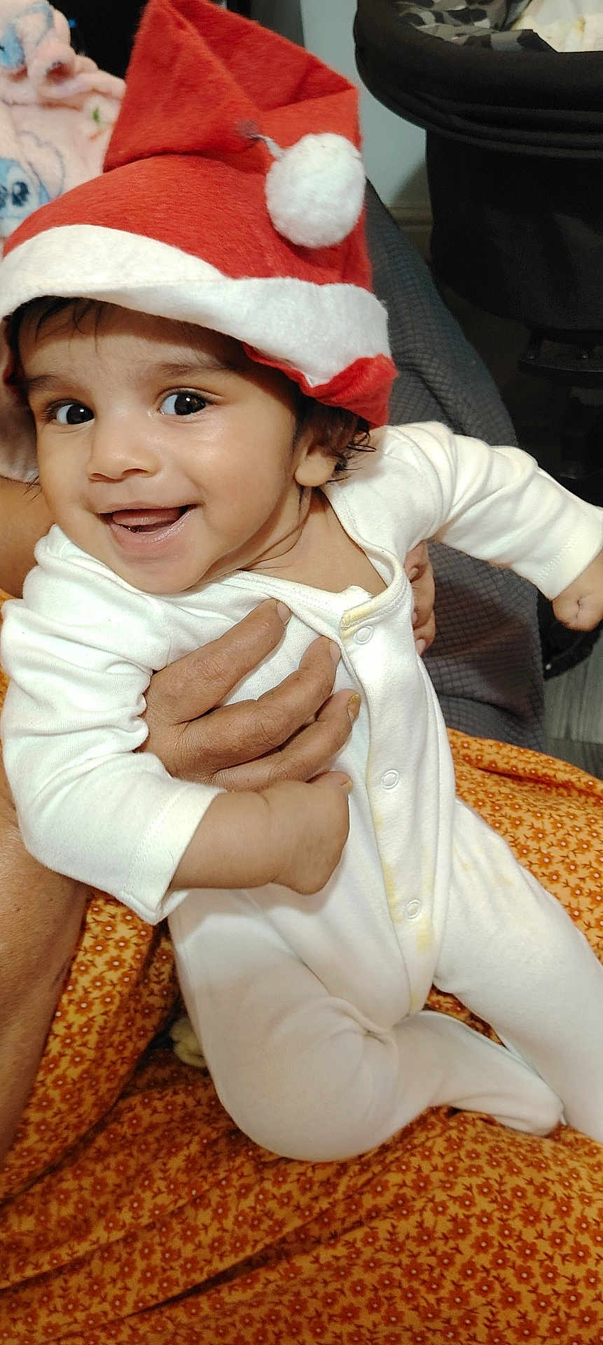 Liam joined the competition — help win amazing prizes! baby, child, smiling, santa_hat, white_onesie, infant, happy, portrait, hand, adult, holding, cozy, indoors, blanket, pattern, cute, festive, holiday, face, person