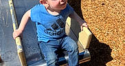 Elijah is registered to the contest to win money with this photo: child, boy, slide, playground, sunlight, wood_chips, blue_shirt, jeans, sneakers, metal_slide, outdoor, daylight, play, fun, casual_clothing, smiling, hair, grip, park, recreation