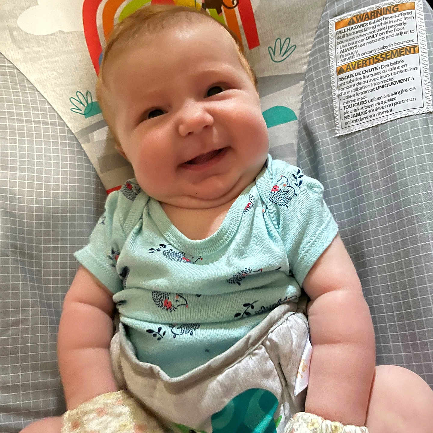 Sophia is registered to the contest to win money with this photo: baby, infant, smile, happy, onesie, mittens, baby_seat, pattern, rainbow, animal_design, indoor, cute, chubby_cheeks, person, child, plush, comfortable, colorful, head, face
