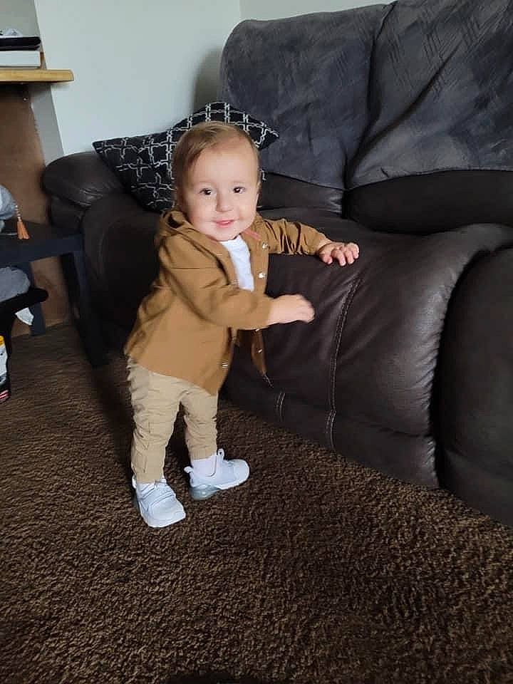 Christopher is registered to the contest to win money with this photo: baby, baby_toddler_clothing, box, comfort, couch, flooring, fun, fur, hardwood, human_leg, joy, knee, lamp, living_room, person, sitting, sleeve, smile, thigh, thumb