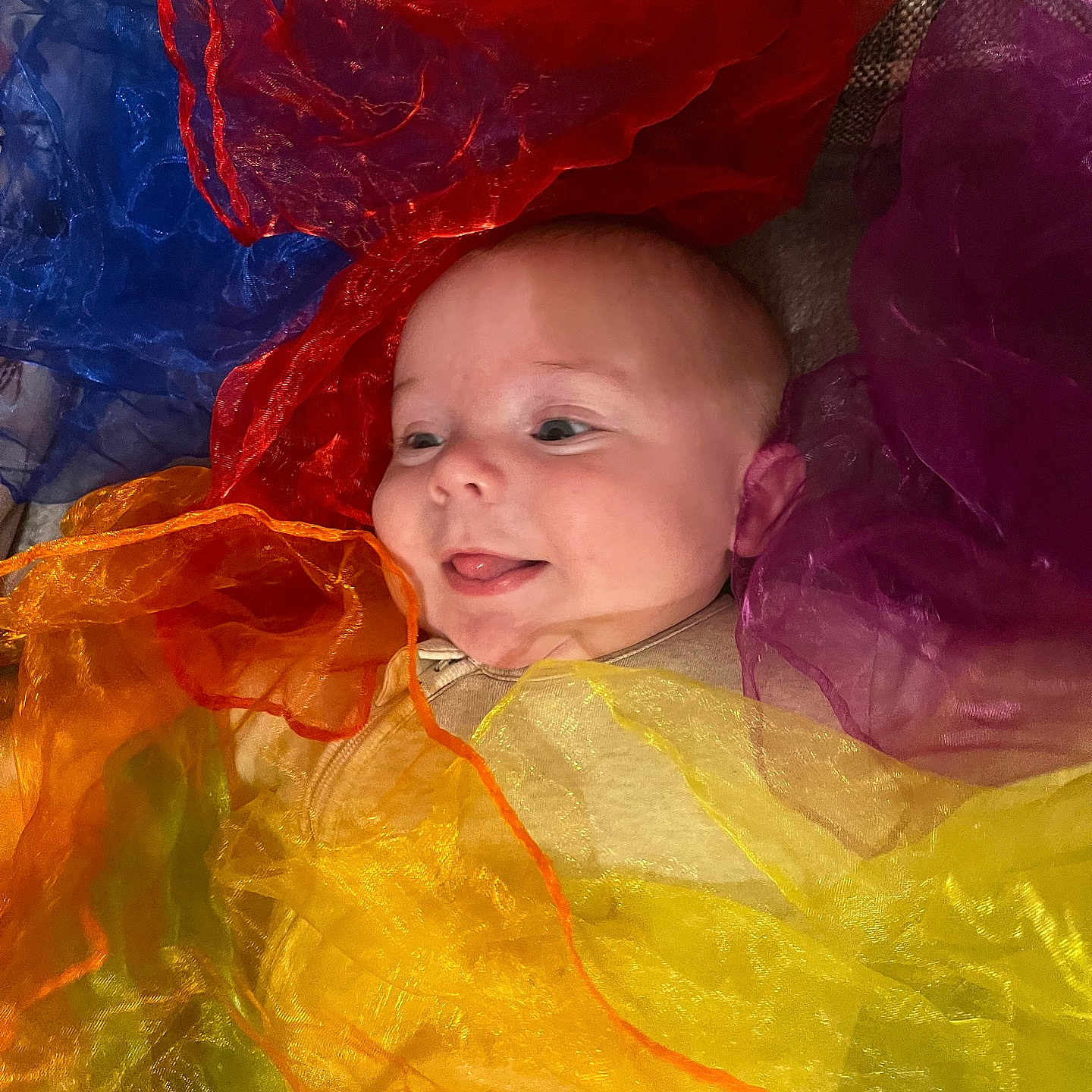 Evan joined the competition — help win amazing prizes! baby, child, closeup, colorful, cute, fabric, face, happy, indoors, infant, multicolor, person, playful, portrait, sheer, smile, soft, texture, tongue, wrapped