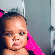 Skylah is registered to the contest to win money with this photo: baby, child, face, skin, blanket, expression, indoor, portrait, pout, curly_hair, person, closeup, infant, cute, young, looking, pink, soft_texture, head, shoulders