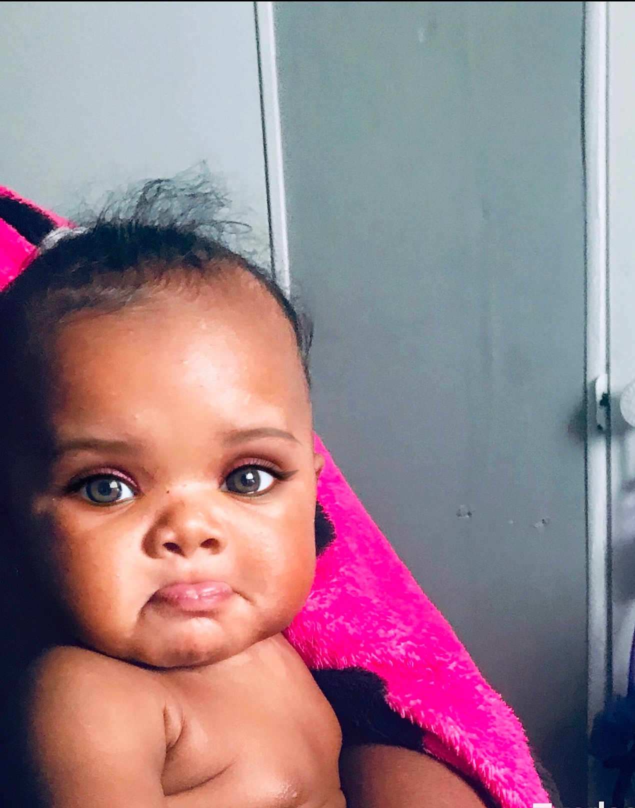 Skylah is registered to the contest to win money with this photo: baby, child, face, skin, blanket, expression, indoor, portrait, pout, curly_hair, person, closeup, infant, cute, young, looking, pink, soft_texture, head, shoulders