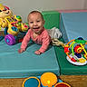 baby, infant, crawling, pink_clothing, playmat, toy, activity_walker, drum_toy, colorful, happy, smiling, indoor, child, floor, wood_floor, play_area, early_childhood, cute, face, person