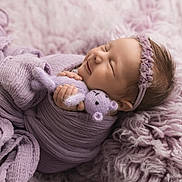 Lainey is registered to the contest to win money with this photo: newborn, baby, sleeping, lavender, blanket, knitted_toy, headband, soft_texture, cozy, wrapped, infant, cute, peaceful, portrait, child, purple, fuzzy, resting, hand, smile