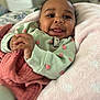 baby, smiling, blanket, bed, infant, cute, clothing, strawberry_print, happy, face, hand, lying_down, comfort, soft_texture, indoors, portrait, cozy, playful, child, cute_baby