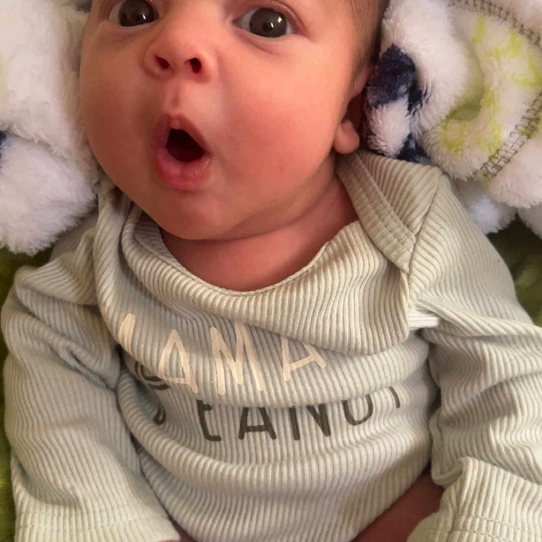 Azriel is registered to the contest to win money with this photo: baby, blanket, bodypart, bonnet, clothing, face, finger, glove, hand, hat, head, knitwear, mouth, newborn, person, photography, portrait, sweater, towel, yawning