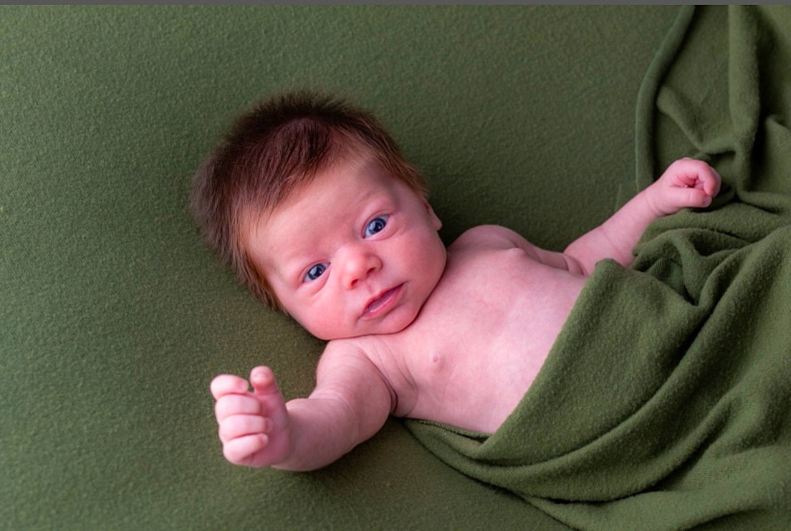 Briggs is registered to the contest to win money with this photo: baby, baby_toddler_clothing, cheek, child, chin, comfort, eye, face, finger, gesture, head, human_body, linens, mouth, neck, nose, person, skin, sleeve, thumb