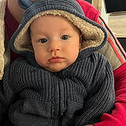 Hugo a rejoint le concours — aidez-le/la à gagner de superbes lots ! baby, child, hoodie, knitwear, indoor, person, adult, face, portrait, warm_clothing, sitting, curious, couch, home, sleeve, hand, television, shelf, red_clothing, cozy
