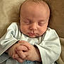 baby, infant, sleeping, hands, clasped_hands, light_blue_clothing, soft_blanket, close_up, peaceful, newborn, cute, face, person, indoor, portrait, baby_clothes, resting, child, young, small_hands