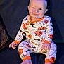 baby, child, pajamas, halloween, pumpkins, ghosts, bats, smiling, sitting, couch, footwearless, blue_eyes, blonde_hair, infant, cute, indoors, comfort, happy, portrait, clothing