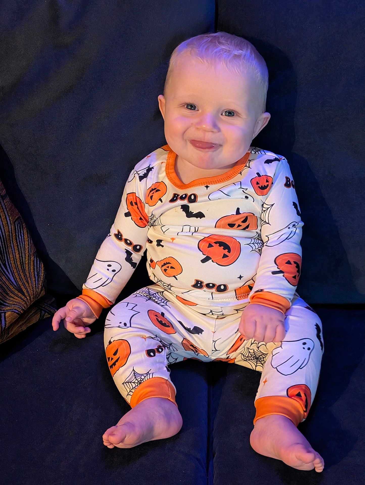 Thomas is registered to the contest to win money with this photo: baby, child, pajamas, halloween, pumpkins, ghosts, bats, smiling, sitting, couch, footwearless, blue_eyes, blonde_hair, infant, cute, indoors, comfort, happy, portrait, clothing