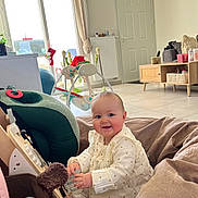 Miya participe au concours pour gagner de l'argent avec cette photo : baby, child, indoor, toy, wooden_toy, smiling, cushion, living_room, furniture, window, curtains, floor, clothing, person, playtime, home, radiator, door, baby_gym, comfort