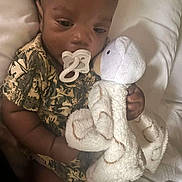 Reazyn is registered to the contest to win money with this photo: baby, pacifier, plush_toy, bear, camo_clothing, infant, child, cute, soft_toy, bed, white_bed, sleepwear, hand, face, lying_down, indoor, resting, comfort, toddler, person