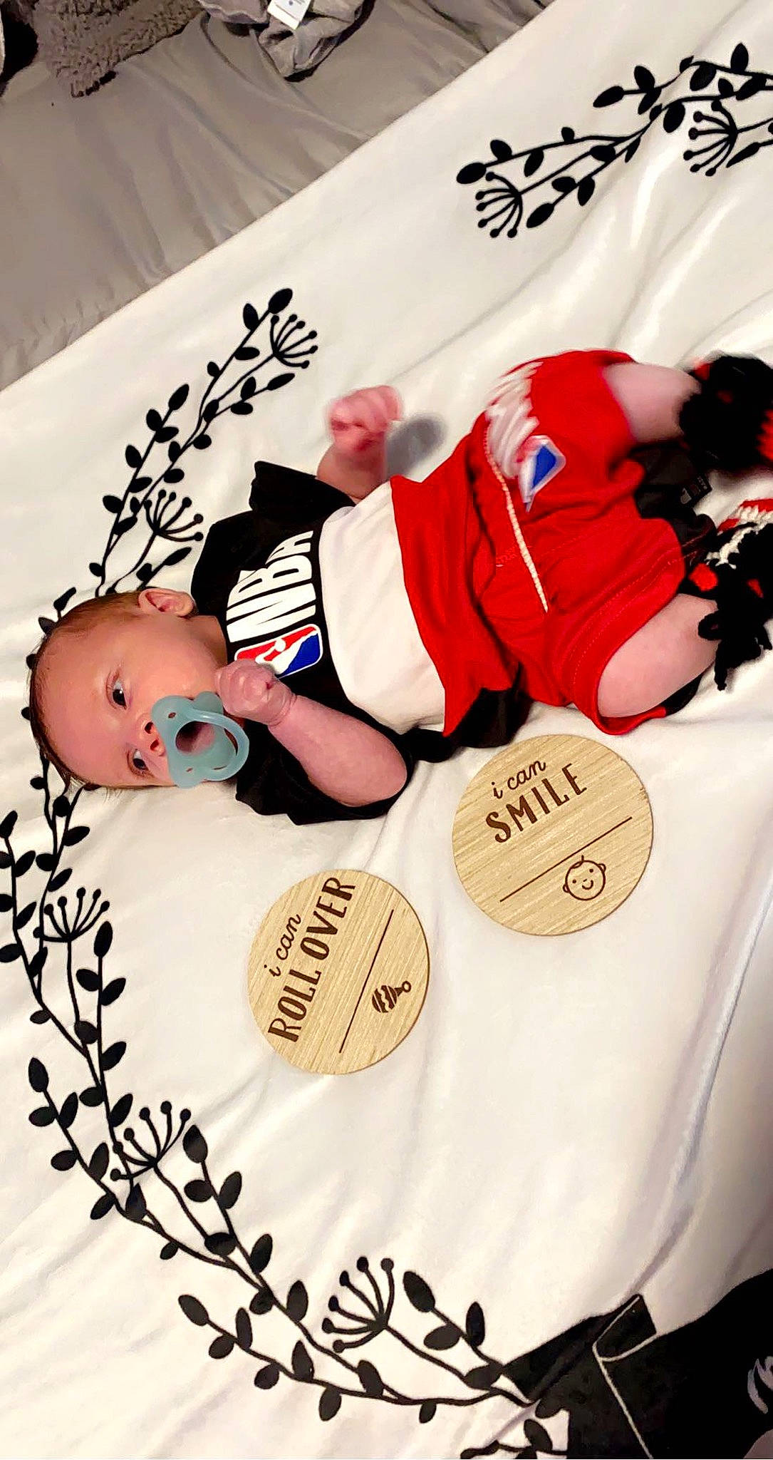 Khamari is registered to the contest to win money with this photo: baby, baby_toddler_clothing, carmine, font, happy, hat, linens, paper, paper_product, pattern, person, player, product, sports_uniform, sportswear, t_shirt, textile