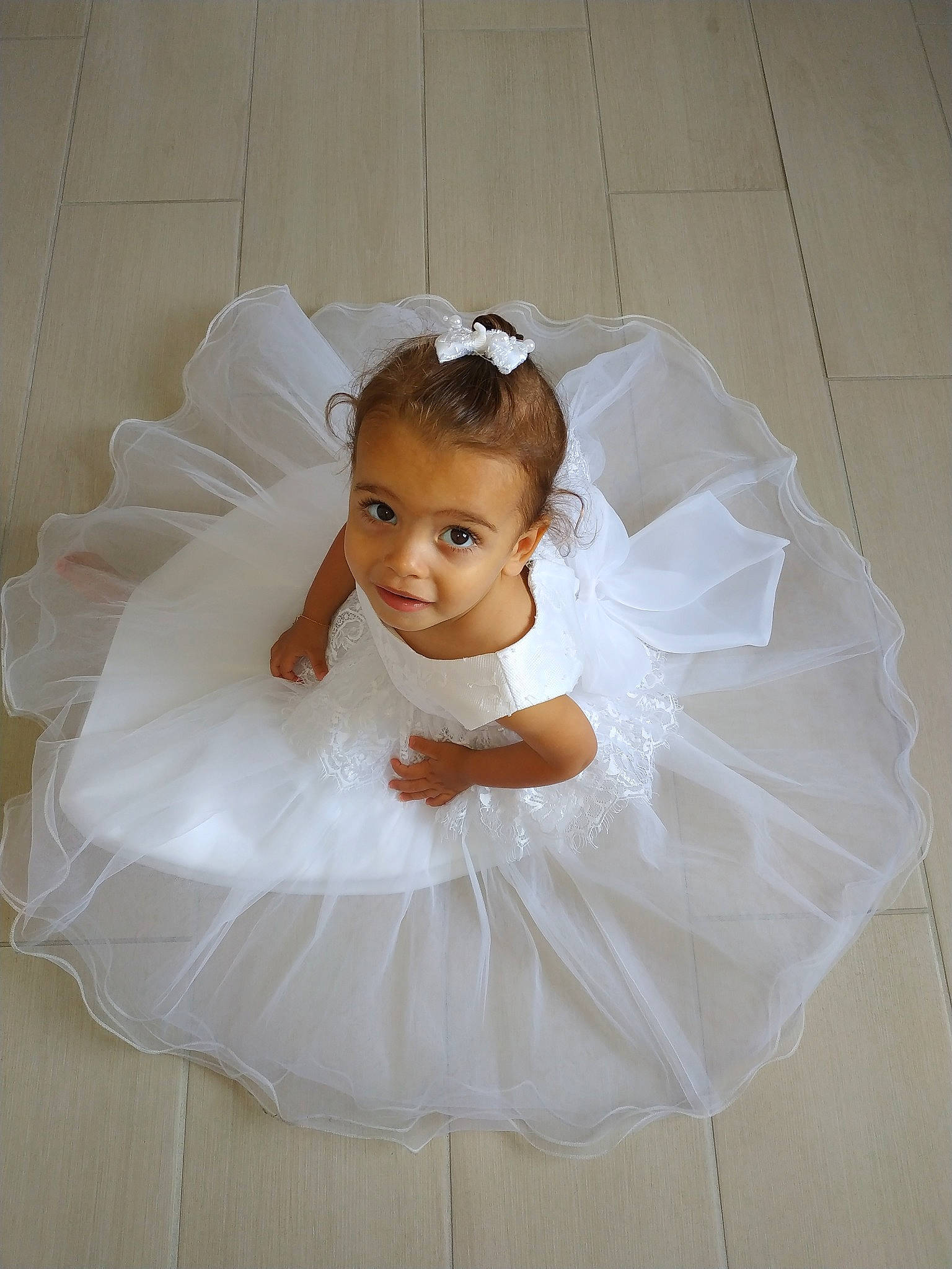 Emma a rejoint le concours — aidez-le/la à gagner de superbes lots ! baby, bridal_accessory, bridal_party_dress, child, costume, dress, flower_girl, hair_accessory, headpiece, person, skin, toddler, white