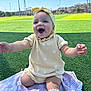 baby, child, smiling, yellow_outfit, headband, blanket, grass, outdoor, sunny, happy, sitting, sock, kneeling, cute, portrait, daylight, field, playful, infant, expression