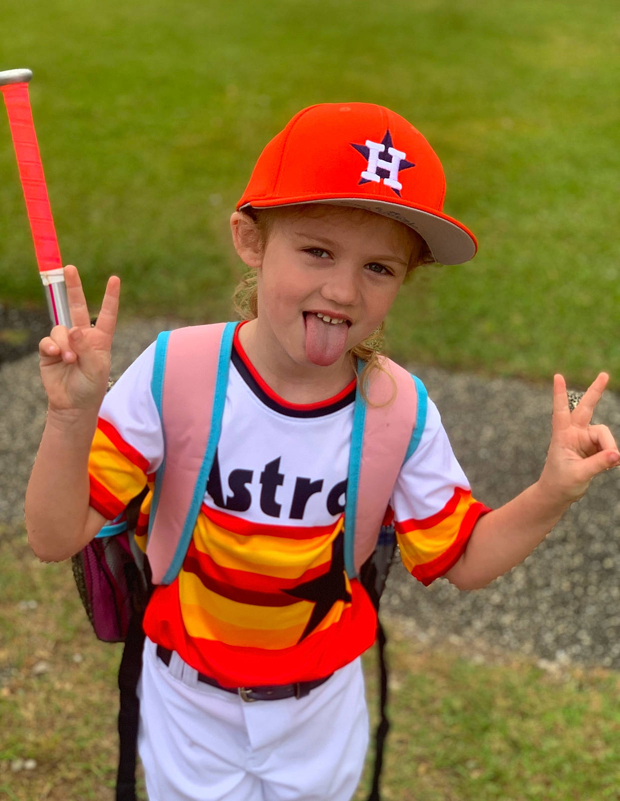 Tegan joined the competition — help win amazing prizes! arm, baseball_cap, cap, child, facial_expression, finger, fun, gesture, grass, hand, happy, headwear, orange, person, personal_protective_equipment, player, recreation, smile, sports, sports_gear
