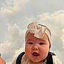 baby, infant, headband, bow, smiling, drool, outdoor, cloudy_sky, cute, happy, face, child, person, clothing, portrait, closeup, expression, joyful, young_child, headwear
