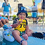 Kylian joined the competition — help win amazing prizes! toddler, child, pool, water, splash, float, hat, goggles, yellow_shirt, smiling, sunny, outdoor, summer, vacation, fun, barefoot, toy, people, blurred_background, happy