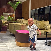 Kylian joined the competition — help win amazing prizes! toddler, child, indoor, lounge, couch, ottoman, pink, plant, floor, tile, clothing, sandals, smiling, walking, furniture, modern, decor, person, portrait, happy