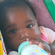 Arianna is registered to the contest to win money with this photo: baby, bottle, milk, blanket, face, hand, child, infant, feeding, closeup, cute, indoors, young, person, skin, eyelashes, clothing, pink, blue, yellow