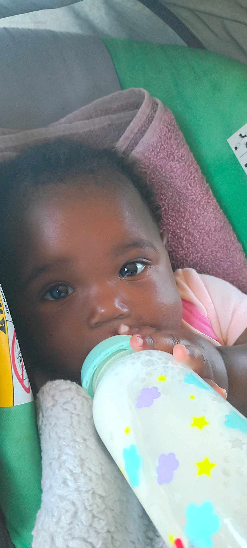 Arianna is registered to the contest to win money with this photo: baby, bottle, milk, blanket, face, hand, child, infant, feeding, closeup, cute, indoors, young, person, skin, eyelashes, clothing, pink, blue, yellow