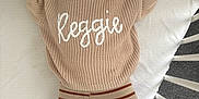 Reggie is registered to the contest to win money with this photo: baby, bed, child, crib, cute, face, furniture, happy, indoor, infant, knitwear, lying_down, person, playful, smiling, socks, striped_pants, sweater, toy, young
