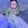 Lilith is registered to the contest to win money with this photo: baby, child, infant, headband, bow, blue_light, pillow, blanket, camo_pants, green_shirt, sitting, indoors, cozy, soft_texture, cute, portrait, young_child, face, eyes, clothing
