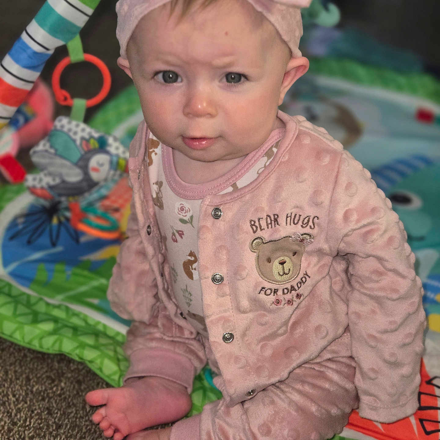 Lilith joined the competition — help win amazing prizes! baby, pink_outfit, headband, bow, play_mat, toy, infant, sitting, curious, indoor, carpet, clothing, face, foot, hand, expression, child, cute, portrait, soft_texture