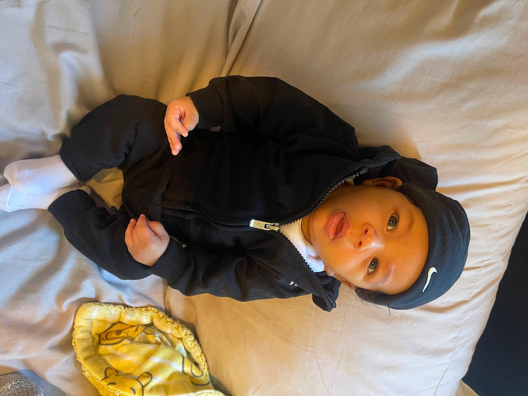 Izaiah is registered to the contest to win money with this photo: bag, comfort, elbow, fun, hat, headwear, linens, person, room, sitting, sleep, sleeve, smile, yellow