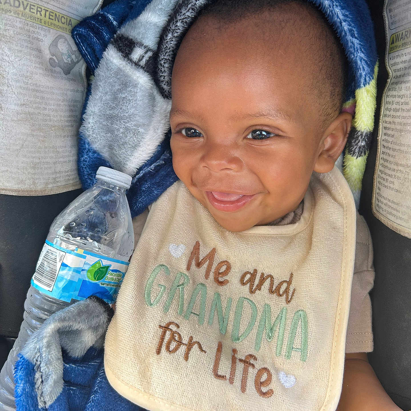 Keyvon joined the competition — help win amazing prizes! baby, smile, bib, blanket, water_bottle, child, cute, happy, person, infant, clothing, seat, car_seat, portrait, closeup, young_child, cozy, expression, face, sitting