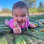 baby, infant, smile, outdoor, blanket, camouflage, happy, grass, nature, child, face, skin, hand, blue_sky, daylight, person, young, cute, playful, portrait