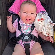Persephone is registered to the contest to win money with this photo: baby, smiling, stroller, pink_onesie, unicorn, blanket, harness, happy, child, infant, cute, blue_eyes, skin, clothing, seat, sunlight, portrait, baby_girl, baby_boy, outdoor