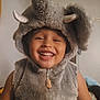 Andre is registered to the contest to win money with this photo: child, smiling, costume, elephant, fluffy, hood, indoor, happy, cute, face, portrait, zipper, furry, playful, young, person, fun, animal_costume, childhood, joy