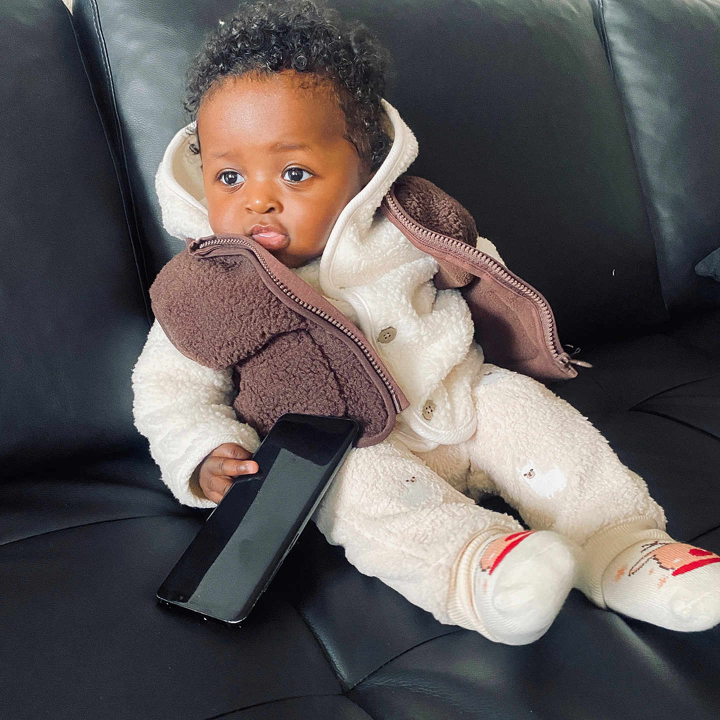 Davi a rejoint le concours — aidez-le/la à gagner de superbes lots ! baby, black, child, clothing, couch, cozy, curly_hair, cute, expression, indoor, jacket, leather, phone, portrait, pout, seated, smartphone, socks, toddler, warm