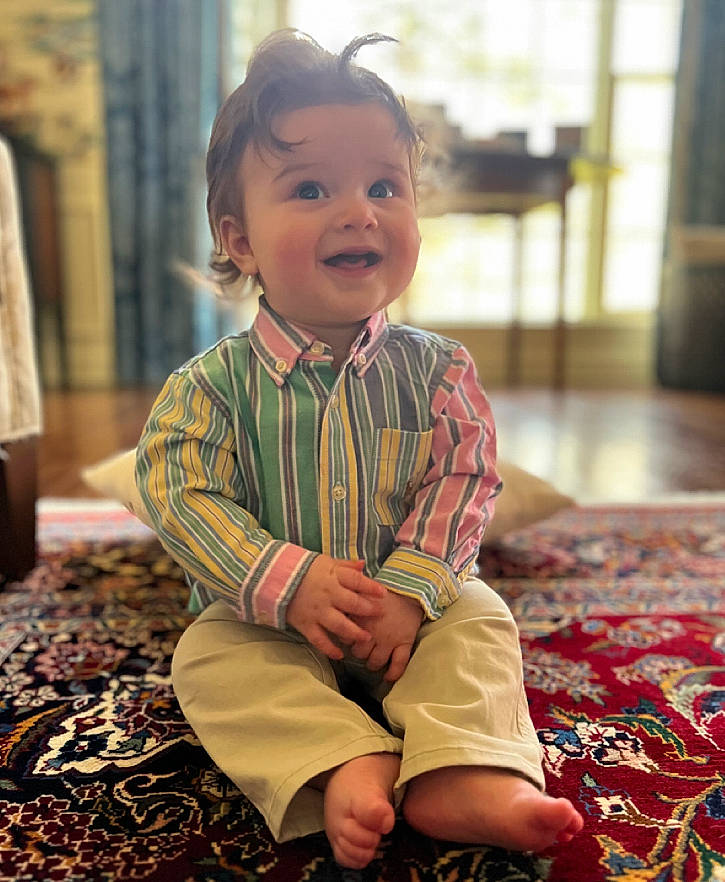 Louis is registered to the contest to win money with this photo: baby, baby_toddler_clothing, cheek, child, face, flooring, fun, hair, happy, head, iris, pattern, person, plant, room, sitting, skin, sleeve, smile, toddler