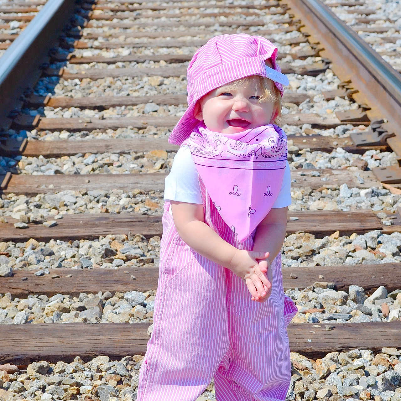 Sadie Mae is registered to the contest to win money with this photo: baby, bonnet, cap, clothing, coat, dress, face, gravel, hat, head, pants, person, photography, portrait, purple, railway, road, rock, rubble, transportation