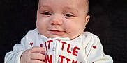 Nathanial joined the competition — help win amazing prizes! adorable, baby, child, closeup, clothing, cute, face, fingers, hand, happy, heart_pattern, infant, onesie, portrait, red_text, sitting, smile, soft_background, warm, young