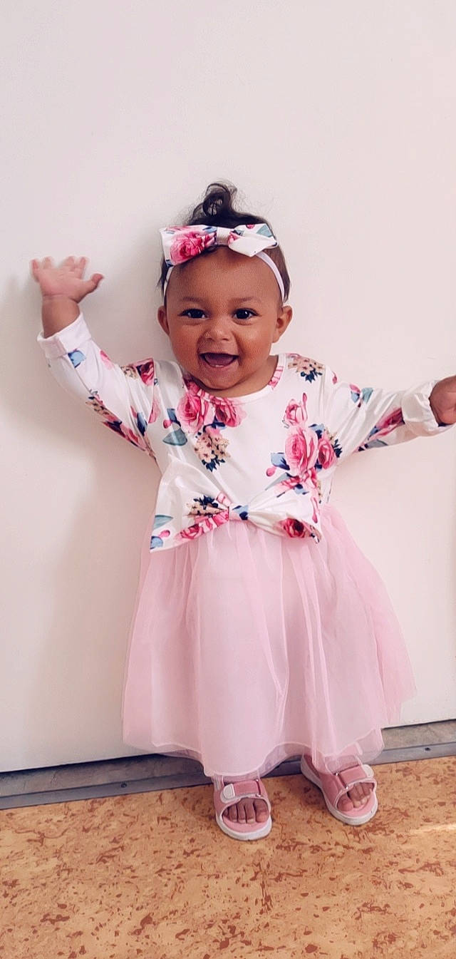 Aminata a rejoint le concours — aidez-le/la à gagner de superbes lots ! baby, baby_toddler_clothing, clothing, day_dress, embellishment, gesture, goggles, hair_accessory, happy, headband, headpiece, joy, magenta, pattern, person, pink, purple, sleeve, smile, textile