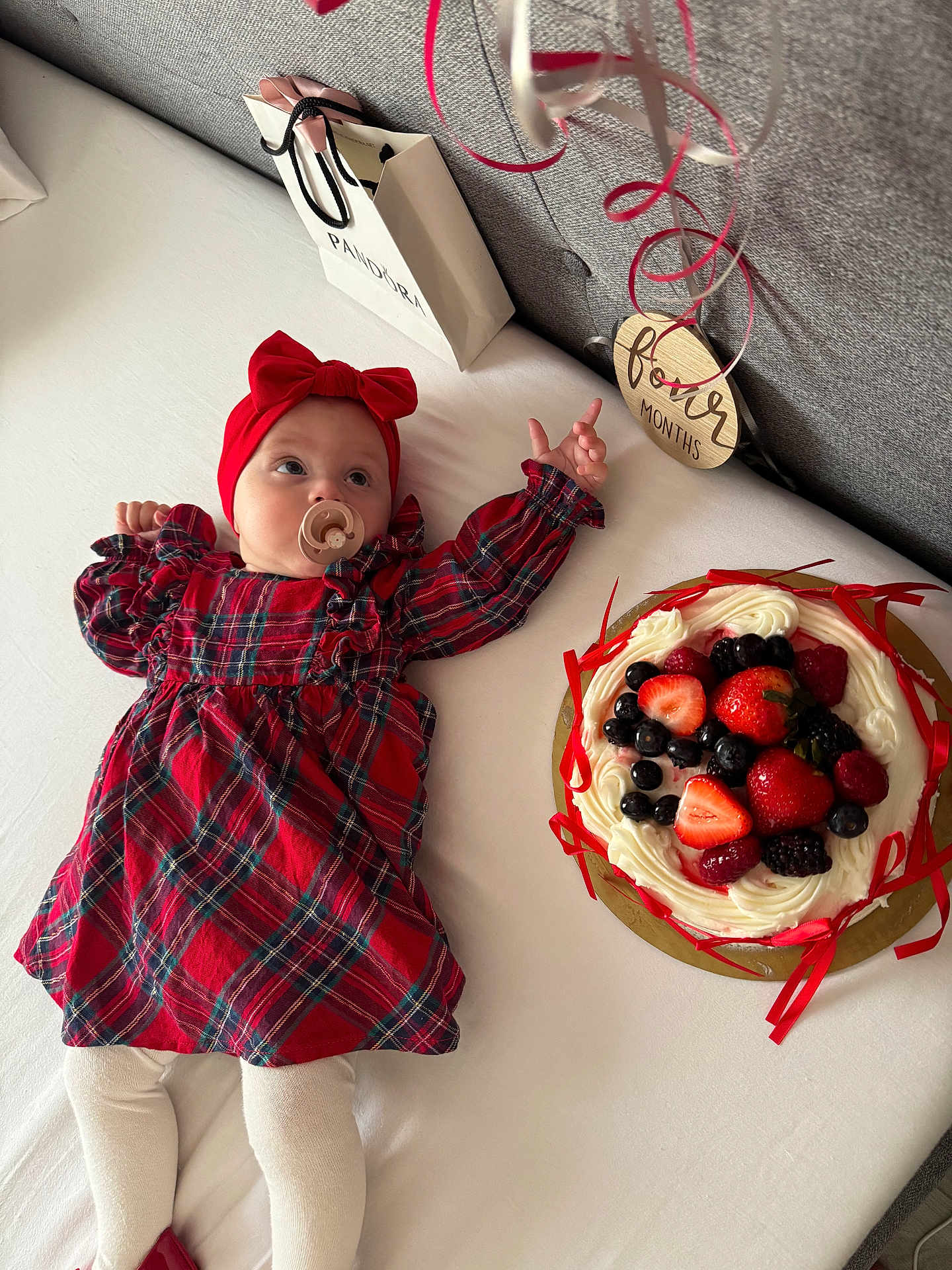 Emilia joined the competition — help win amazing prizes! baby, infant, red_dress, headband, pacifier, bed, cake, fruit, strawberries, blueberries, blackberries, raspberries, ribbons, gift_bag, pandora, celebration, four_months, plaid, white_bed, cute