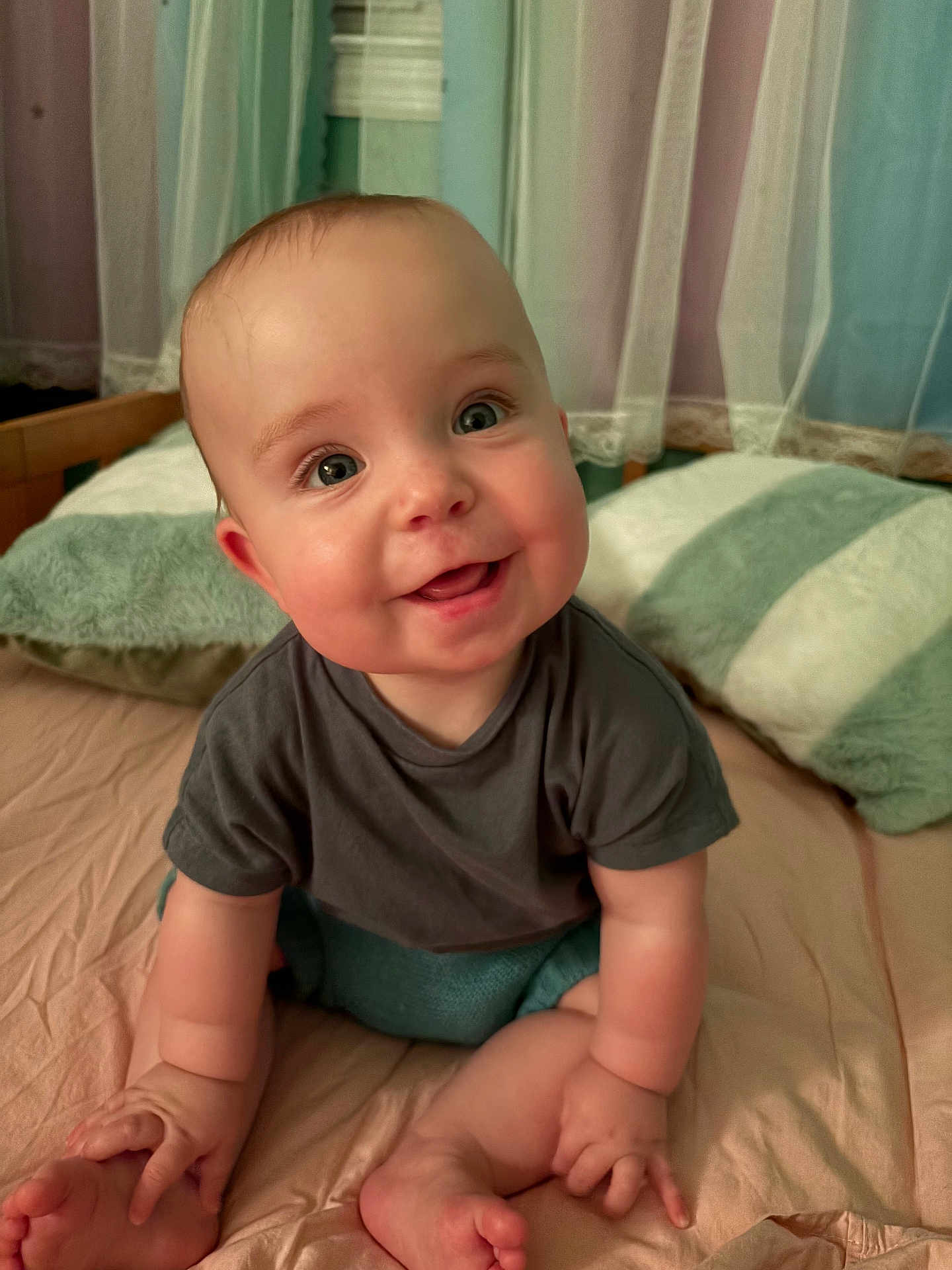 Poppy is registered to the contest to win money with this photo: baby, smile, happy, child, infant, bed, pillow, curtain, indoors, cute, sitting, clothing, skin, face, eyes, hands, feet, soft, cozy, portrait