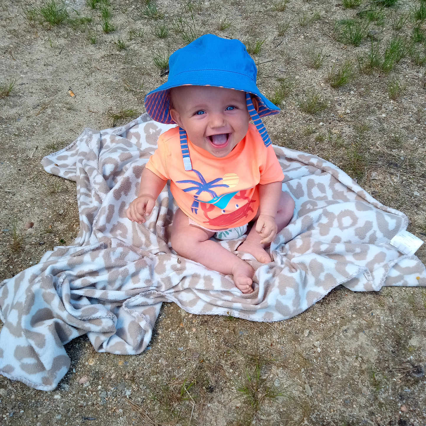 Mikey is registered to the contest to win money with this photo: baby, baseballcap, blanket, cap, clothing, dress, face, grass, hat, head, nature, outdoors, park, person, photography, plant, portrait, soil, summer, sunhat