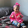 bed, blanket, casual_clothing, child, clapping, cute, happy, headband, home, indoors, patterned_blanket, person, pink_clothing, playful, portrait, seated, smiling, socks, toddler, young_child