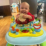 River joined the competition — help win amazing prizes! baby, child, walker, toy, indoor, floor, wooden_sign, red_clothing, smiling, tongue_out, happy, playful, colorful, furniture, home, flooring, person, infant, cute, baby_toy