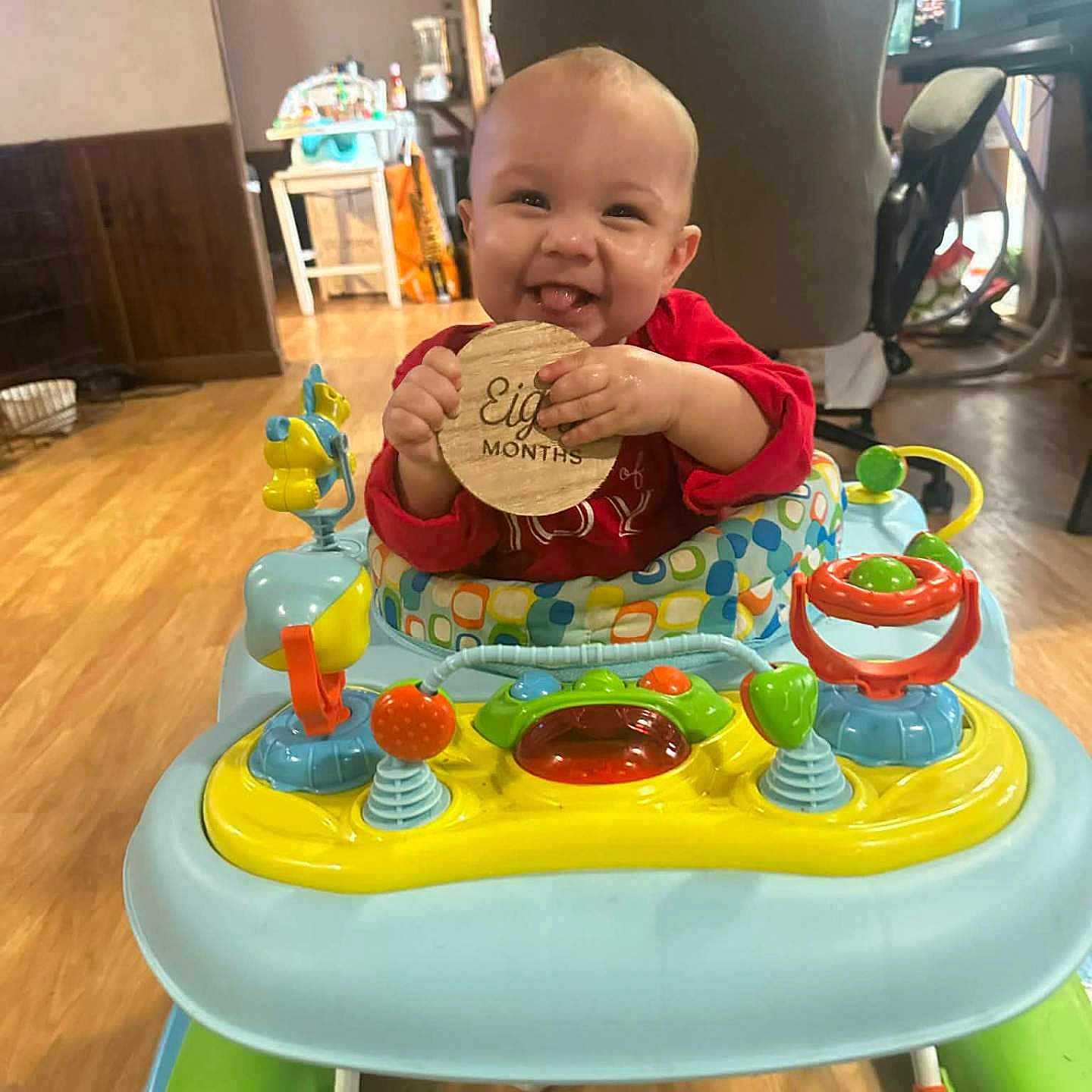 River joined the competition — help win amazing prizes! baby, child, walker, toy, indoor, floor, wooden_sign, red_clothing, smiling, tongue_out, happy, playful, colorful, furniture, home, flooring, person, infant, cute, baby_toy