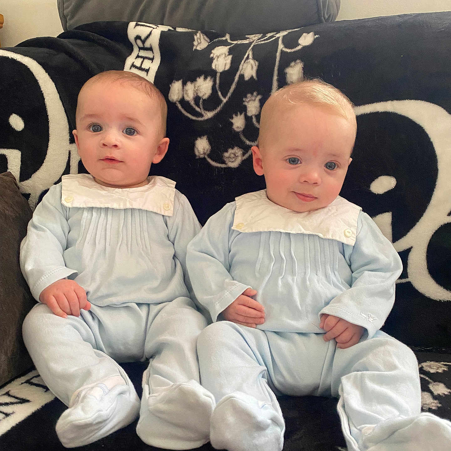 Johnny And Joey joined the competition — help win amazing prizes! baby, blanket, blue_outfit, child, couch, cozy, cute, face, footed_pajamas, hands, homedecor, indoor, infant, looking_at_camera, portrait, seated, soft_lighting, twins, two_people, young