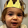 toddler, child, crown, golden_crown, paper_crown, sweater, beige_sweater, snowman_pattern, indoor, portrait, face, curly_hair, messy_hair, smile, cute, young_child, baby, expression, cozy, warm_clothing