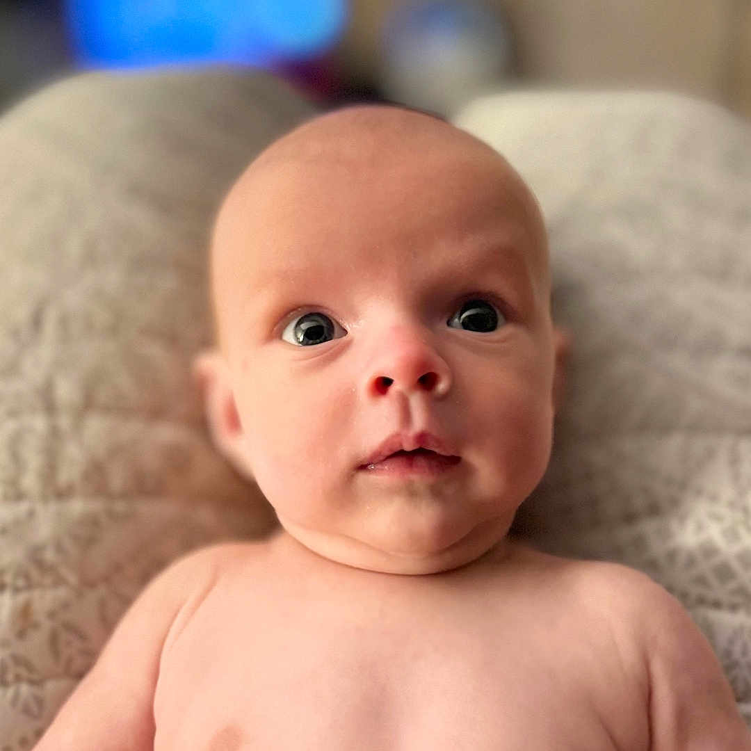 Kashton Smith is registered to the contest to win money with this photo: baby, bare_chest, child, chubby, curious, cute, expression, eyes, face, head, indoor, infant, lying_down, newborn, person, portrait, quilt, skin, soft, young